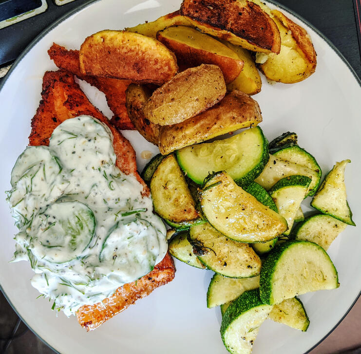 baked salmon, potato wedges, and zucchini with homemade tzatziki sauce